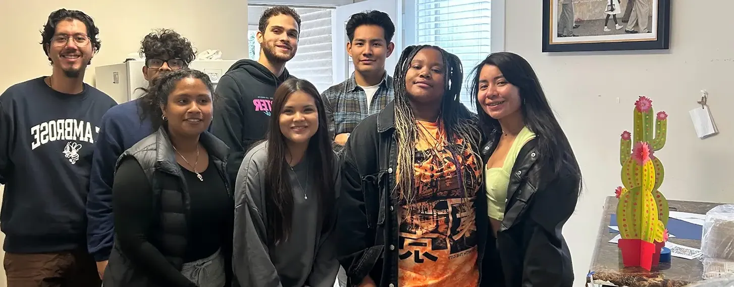 A group of students from latino unidos posing in front of the Greater Quad Cities Hispanic Chamber of Commerce.